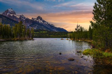 ABD 'nin Wyoming şehrinde Taggart Gölü ve Grand Teton Dağları üzerinde gün batımı. Taggart Gölü Grand Teton Ulusal Parkı 'nda görkemli dağlarla çevrili çarpıcı bir alp gölüdür..