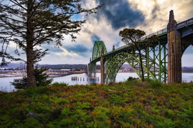 Newport, Oregon 'daki Yaquina Körfezi Köprüsü üzerinde bulutlu gökyüzü ile gün batımı. Yaquina Körfezi Köprüsü, görkemli körfezin üzerinde uzanan zarif bir sanat deco yapısıdır..