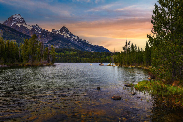 Sunset over Taggart Lake and Grand Teton Mountains in Wyoming, USA. Taggart Lake is a stunning alpine lake in Grand Teton National Park, surrounded by majestic mountains.