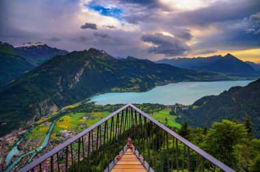 Harder Kulm 'un Interlaken, Thunersee ve İsviçre Alpleri' ne tepeden bakan günbatımı manzarası, İsviçre 'de dramatik bulutlar ve yemyeşil vadiler.