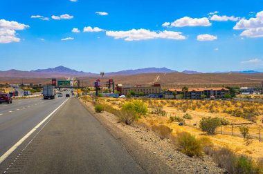 Barstow, California, ABD - 17 Haziran 2023 Mojave Otoyolu I-15 'te güneşli bir gün trafik, ticari tabelalar ve dağlık zemin.