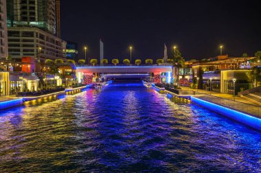 Manama, Bahreyn - 27 Aralık 2023: Geceleyin Bahreyn Körfezi 'ni aydınlatmak, suları yansıtan renkli ışıklar, modern mimari ve Manama, Bahreyn' de canlı bir atmosfer.