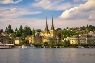 Lucerne, Switzerland - June 27, 2024 : A view of Lucernes iconic twin spires of the Church of St. Leodegar, set against the picturesque cityscape along Lake Lucerne. clipart