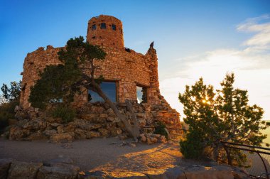 Tarihi bir taş yapı olan Desert View Watchtower, Arizona, ABD 'de günbatımında Büyük Kanyon Güney Rim' de duruyor ve kanyon manzarası ile çöl manzarası sunuyor..