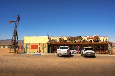 Kingman, Arizona, ABD - Kasım 04, 2023: Kingman, Arizona yakınlarındaki tarihi Route 66 'da Rustik yol kenarı bar ve karavan parkı, yel değirmeni, klasik araba dekoru ve çöl çevresi.