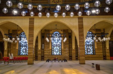 Manama, Bahreyn - 24 Aralık 2023: El Fetih Büyük Camii 'nin içi kemerli sütunlar, karmaşık boyalı camlar ve küresel ışıklar sergileniyor.