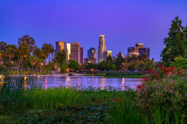 Los Angeles şehir merkezindeki gökyüzü mavi saatte Echo Park 'tan izleniyor. Sahnede şehir ışıkları, palmiye ağaçları ve sakin bir göl yer alıyor..