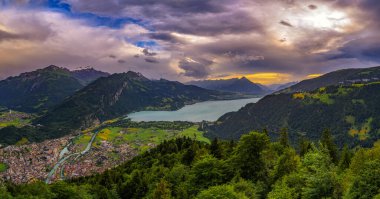 Harder Kulm 'dan Interlaken, Thunersee ve İsviçre Alpleri' ne tepeden bakan günbatımı manzarası. İsviçre 'de dramatik bulutlar ve yemyeşil vadiler var..
