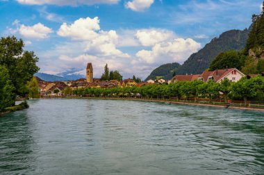 İsviçre 'nin Interlaken kentinin manzarası, arka planda Aare Nehri ve İsviçre Alpleri ile geleneksel binalar ve yemyeşil alanlar yer alıyor..