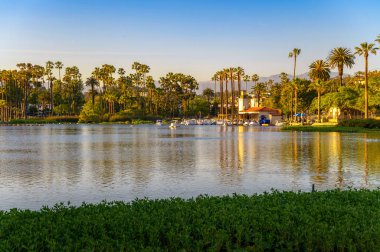 Los Angeles, Kaliforniya, ABD - 21 Haziran 2023: Los Angeles, Kaliforniya 'da Echo Park Gölü manzaralı bir gün batımı manzarası, palmiye ağaçları, pedal botları ve bir kayıkhane.