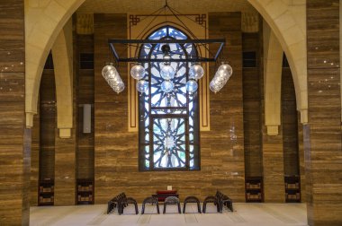 Manama, Bahreyn - 24 Aralık 2023: El Fetih Büyük Camii 'nin merkezi namaz alanı, sandalyeler, boyalı camlar ve kemerli kolonların çerçevelediği asılı ışıklar.