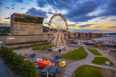 Oslo, Norveç - 30 Temmuz 2024: Modern Munch Müzesi ve günbatımında rıhtımdaki dönme dolap. Burası Norveçli sanatçı Edvard Munch 'un yaşamı ve eserlerine adanmış bir sanat müzesi..