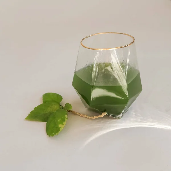 Vitamins for life. Green powder. Cocktail. Supplements. In a transparent glass. Light background. Sunlight. Cozy and healthy breakfast. High quality photo
