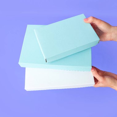 Mor arka planda uzun kutular, el ele tutuşmalar. Mesaj ve logo için yer. Paketleme konsepti, hediye. Yüksek kalite fotoğraf