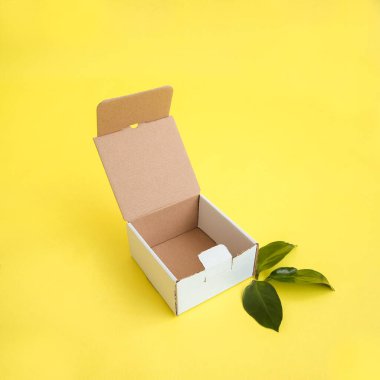 Sarı arka planda beyaz sandığı açın. Mesaj ve logo için yer. Eko tarzı. Paketleme konsepti, şirketin tek bir stili, markalaşma, hediyeler, tatil. Yüksek kalite fotoğraf