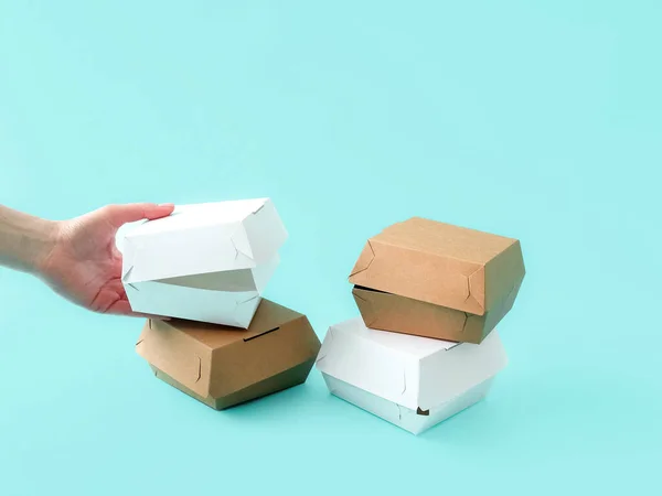 Boxes for packing sandwiches on a blue background , human hands. Place for text and logo. The concept of food, delivery, uniform style, branding of the company. Eco style. High quality photo