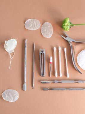 Kahverengi arka planda beyaz çiçek yapraklı manikür kesiciler. Güzellik salonu, estetik, metin için bir yer var. Yüksek kalite fotoğraf