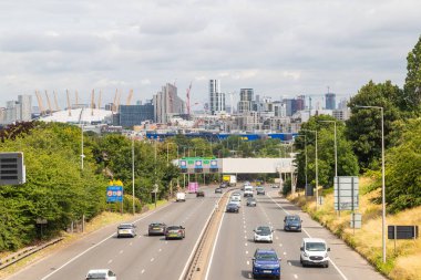 LONDON, UK - 13TH JULY 2023: Traffic on the A2 road in South East London connecting with the Black Wall tunnel. Part of the O2 dome can be seen. clipart