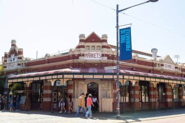 FREMANTLE, AUSTRALIA - 13TH OCT 2024: The outside of Fremantle Market showing one of the entrances and signs. People can be seen in and around the building. clipart