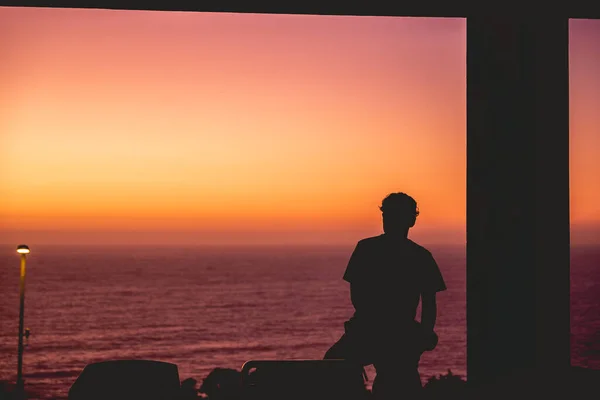 Silhouette of a person in a terrace in front of the beach with colorful sunset
