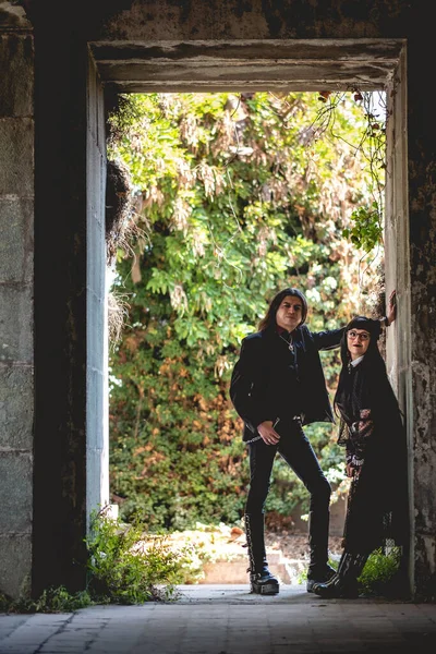 Dark gothic couple in a big gate in a large ancient abandoned mausoleum ruins in neoclassical style
