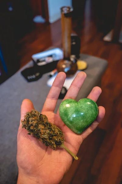 Hand Hält Einen Herzförmigen Grünen Jadestein Und Eine Große Marihuanaknospe — Stockfoto