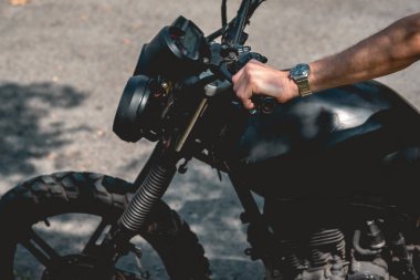 Güneşli bir günde eski bir motosiklete binen saatli ellerin ayrıntıları