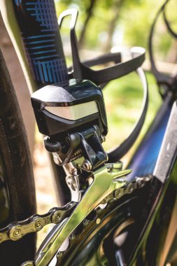 Güneşli bir günde parkta raydan çıkarıcı ve profesyonel bisiklet zinciri ile ilgili detaylar.