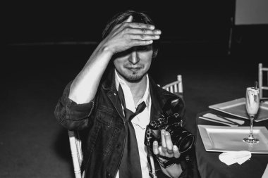 Çekici genç fotoğrafçı gecenin bir yarısı bir düğünde el feneriyle çekimleri kontrol ediyor.)