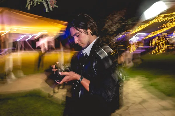 Привлекательный Молодой Фотограф Проверяет Снимки Свадьбе Ночью Размытыми Фарами Заднем — стоковое фото