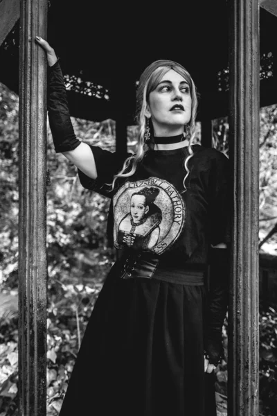 髪のスカーフと暗い服とスカートを持つ若い女の子は 古い世紀の展望台で午後に公園 黒と白で — ストック写真