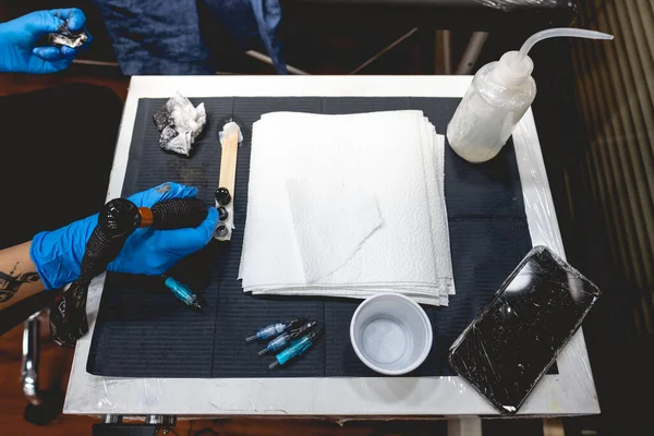 Tetoválógépet Tartó Tetováló Művész Kezei Fekete Tintával Töltve Munkaasztal Tűkkel — Stock Fotó