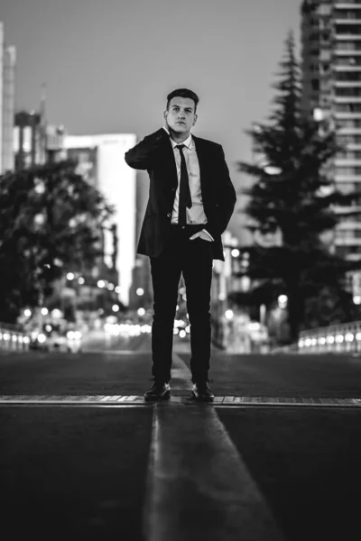 街のダウンタウンの真ん中に黒のスーツを着た若くて魅力的なモデルの男 黒と白で — ストック写真