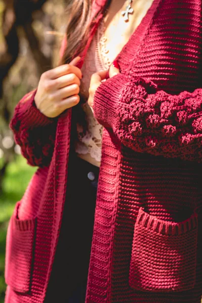 Stock image Closeup of girl with beautiful hands, dark nails and deep red sweater (with fabric details) in sunny park