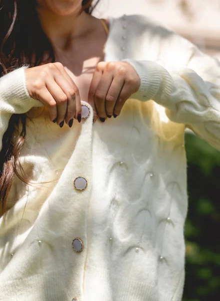 在阳光明媚的公园里用漂亮的手 深色的钉子和白色的毛衣 有面料的细节 给女孩穿上的衣服 — 图库照片