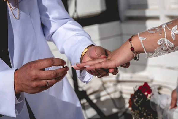 The perfect love moment: detail of hands of groom putting ring on bride\'s finger