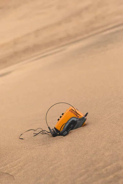 老式技术 老式的黄色随身听个人立体声盒式磁带唱机 停在沙漠的沙滩上 有很大的复制空间 — 图库照片