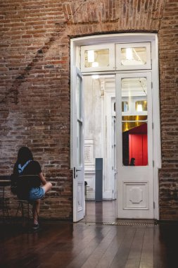 Eski yüzyılların kırmızı tuğlalı sarayında oturan genç bir gezgin kız büyük beyaz bir kapısı, dekoratif detayları ve güneş ışığıyla