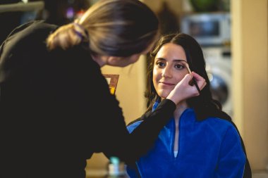 Hazırlığın güzelliği: bir makyöz güzel ve genç bir esmer modeli fotoşop için hazırlıyor.