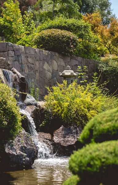 stock image Peaceful zen oasis: japanese garden adorned with a gentle waterfall, serene pond, stone lamp, and lush greenery on a sunny day