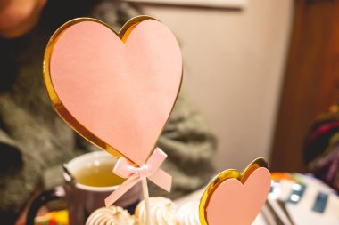 Masadaki kremalı pastanın üzerinde fotokopi alanı olan pembe ve altın kalp dekorasyonu.