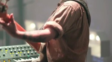 Klasik titreşimler ve müzik yeteneği: Genç Latin basçı ve dövmeli, gömlekli ve gözlüklü klavyeci renkli ışıklar altında krem levrek ve klasik klavyeyle canlı konser veriyor