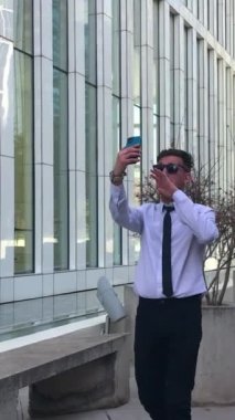 Profesyonel, çekici ve kendine güvenen genç iş adamı beyaz gömlekli ve siyah kravatlı şarkı söyleyip dans ederken sosyal medyada kendini kaydetmiş.