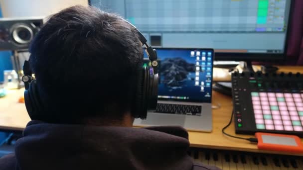 クリエイティブミュージックアーティスト 彼の音楽スタジオに没頭した大きなヘッドフォンでメロディーを制作する若い男 — ストック動画