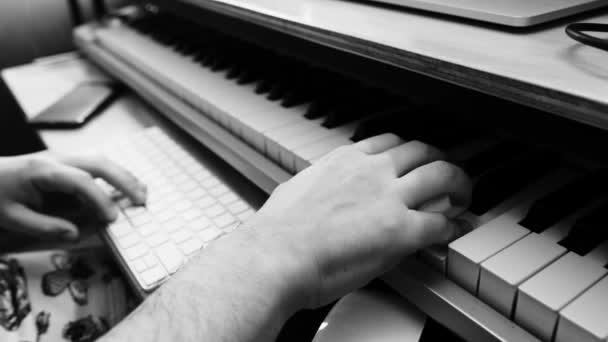 Creative music production: expert musician hands creating with mouse, keyboard, and playing electric keyboard piano (in black and white)