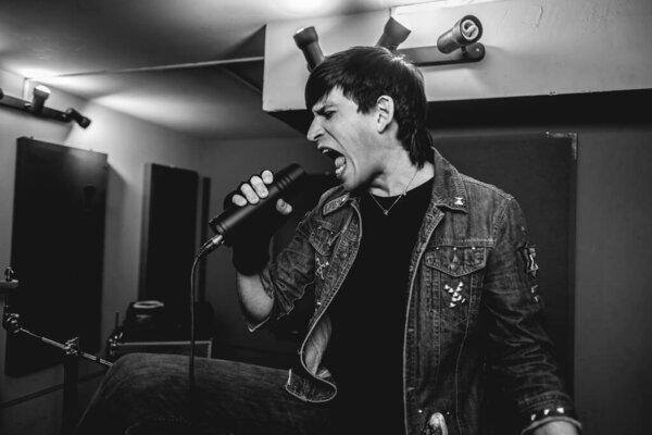Passionate and intense young rocker vocalist unleashing raw energy during intense metal performance in a rehearsal room (in black and white)