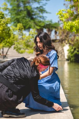 Hazırlığın güzelliği: bir makyöz güzel ve genç bir esmer mankeni parkta fotoğraf çekimine hazırlıyor.