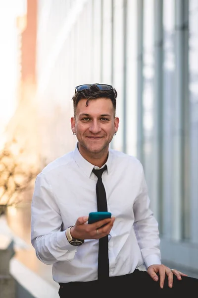 Urban business lifestyle: modern and young professional with white shirt and black tie using a phone in business district