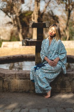 Japon güzeli: Geleneksel beyaz ipek kimonolu Asyalı sarışın kadın güneşli bir günde Japon bahçesinde yapraklar dizayn edilmiş.