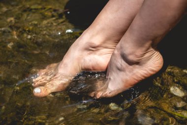 Parlak güneş ışığı altında kristal berrak kaynak suyuna batırılmış beyaz tırnaklı zarif ayakların huzur içinde dinlenmesi.